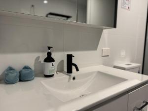 a sink in a bathroom with a bottle of soap at Modern Simplicity Granny Flat in Belmont in Brisbane +11 photos