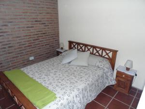 a bedroom with a bed and a brick wall at Cabañas los amigos Pino in Potrero de Garay