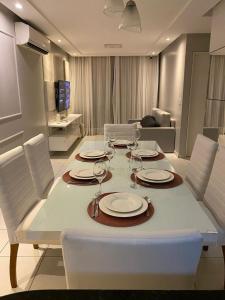 a dining room table with plates and wine glasses at Apartamento Bessa Luxo in João Pessoa