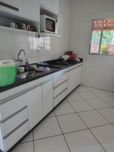 una cucina bianca con un lavello e un forno a microonde di Casa próxima ao estádio do Atlético mg a Belo Horizonte