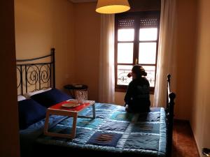 una niña sentada en una cama mirando por la ventana en Selgas de Cudillero en Cudillero