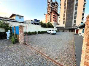 a parking lot with a white car parked next to buildings at Pousada Brisa Garden - Penha in Penha
