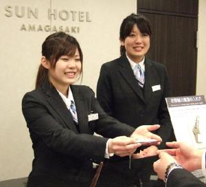 two women in suits are shaking hands in a room at サンホテル尼崎 in Amagasaki