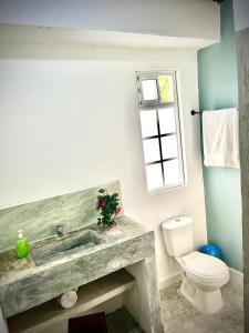 een badkamer met een wastafel en een toilet en een raam bij CALABAZO Casa MonoCai in Santa Marta