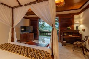 ein Schlafzimmer mit einem Bett, einem Schreibtisch und einem Fernseher in der Unterkunft Puri Wulandari A Boutique Resort & Spa in Ubud