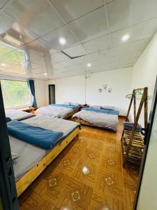 two beds in a room with a wooden floor at Thanh Bình Homestay Khu 37 Hộ Măng Đen in Kon Plong