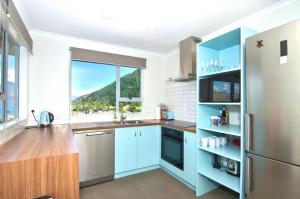 a kitchen with blue cabinets and a large window at Panoramic Views! Luxurious Townhouse in the Absolute Centre of Queenstown in Queenstown +10 photos