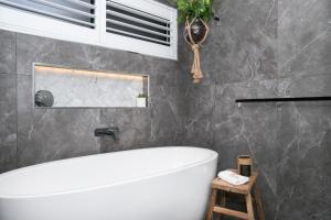 a bathroom with a white bath tub in a room at Mimosa House - 250m to Chinamans Beach in Jervis Bay! in Hyams Beach +13 photos