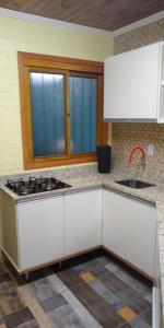 a kitchen with white cabinets and a sink and a stove at Cabana Aconchegante in São Francisco de Paula