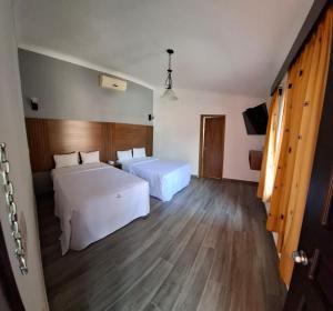 a hotel room with two beds and a television at Hotel Aquiles in Guadalajara