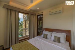 a bedroom with a bed with a view of a balcony at StayVista at Gulmohar Estate - 5BR Luxury House in Kasauli with Bonfire, BBQ & Lawn in Kasauli +25 photos