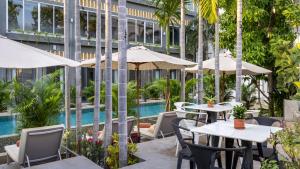 an outdoor patio with tables and umbrellas next to a building at Reservoir, Yoga & Wellness Retreat in Siem Reap