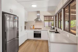 a kitchen with white cabinets and a stainless steel refrigerator at Majuvary in Dunsborough +11 photos