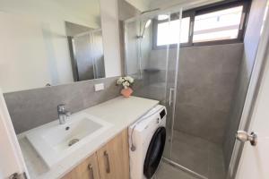 a bathroom with a sink and a washing machine at A2 Airport 2BR Haven - Garden & Parking in Perth