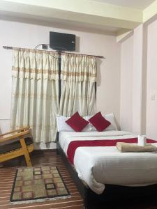 a hotel room with two beds and a television on the wall at Hotel Blue lake in Pokhara
