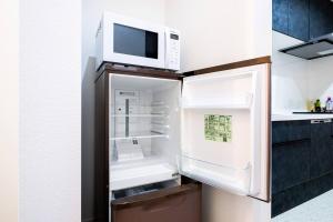 einen offenen Kühlschrank mit einer Mikrowelle darüber in der Unterkunft White Hotel Tsuruhashi in Osaka