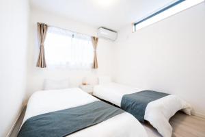 zwei Betten in einem weißen Zimmer mit Fenster in der Unterkunft White Hotel Tsuruhashi in Osaka + 67 Fotos