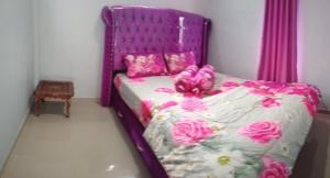 a purple bed with pink flowers on it in a bedroom at Hafiz Homestay in Pagaralam