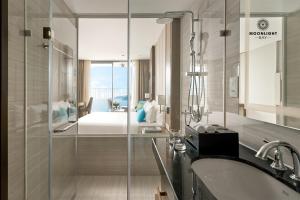 芽庄Moonlight Bay Panorama Condotel Ocean View的带淋浴和盥洗盆的浴室以及1张床。