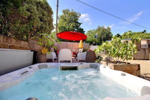 a hot tub in a backyard with an umbrella at La villa de la lieue de greve in Plestin-les-Grèves