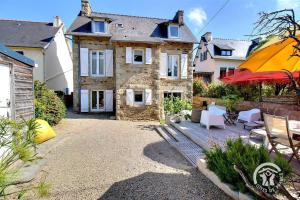 a large stone house with a patio with tables and chairs at La villa de la lieue de greve in Plestin-les-Grèves