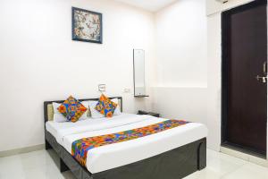 a white room with a bed with colorful pillows at FabHotel Rachana Residency - Nr Shivaji Nagar Metro Station and Railway Station in Pune