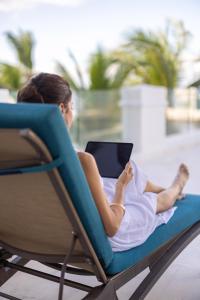 a woman sitting in a chair with a tablet at Cozumel Palace-All Inclusive in Cozumel +65 photos