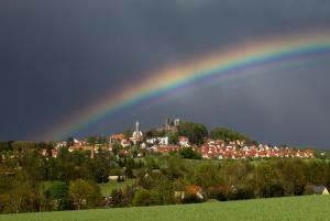 um arco-íris no céu sobre uma cidade em Burghotel Stolpen em Stolpen