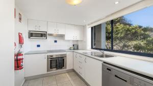 a white kitchen with a sink and a window at 213 South Pacific Apartments in Port Macquarie