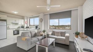 a living room with two couches and a table at Unit 24 Fountain Court in Port Macquarie