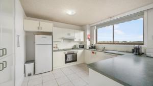 a kitchen with white appliances and a large window at Unit 24 Fountain Court in Port Macquarie +7 photos