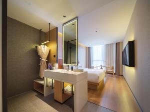 a bathroom with a sink and a bed and a mirror at 桔作酒店 新乡东站市政府店 in Xinxiang