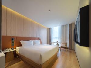 a hotel room with a large bed and a tv at 桔作酒店 新乡东站市政府店 in Xinxiang