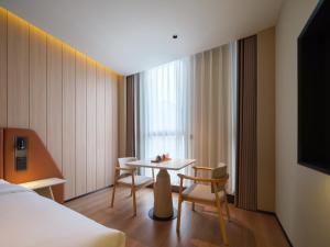 a hotel room with a table and a bed at 桔作酒店 新乡东站市政府店 in Xinxiang