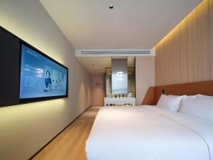 a bedroom with a large bed and a flat screen tv at 桔作酒店 新乡东站市政府店 in Xinxiang