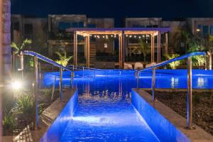a swimming pool at night with blue water at Tasman Holiday Parks - Papamoa Beach in Papamoa