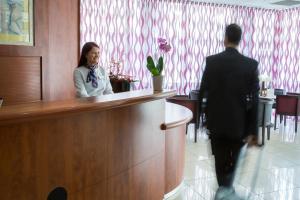 a man and a woman standing at a counter in a lobby at Mercure Béziers in Béziers