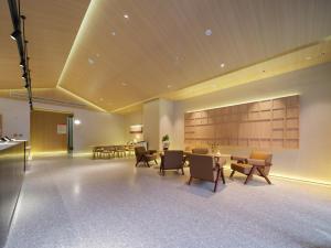 a lobby with tables and chairs in a building at 桔作酒店 新乡东站市政府店 in Xinxiang