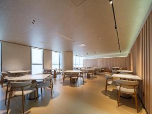 a dining room with tables and chairs and windows at 桔作酒店 新乡东站市政府店 in Xinxiang