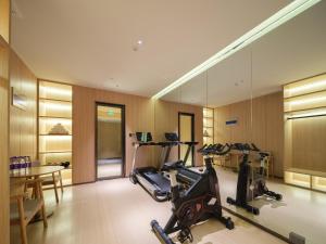 a fitness room with a treadmill and a table at 桔作酒店 新乡东站市政府店 in Xinxiang