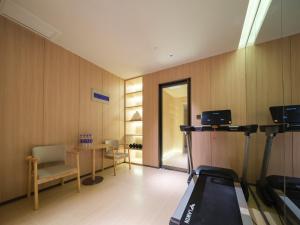 a room with a treadmill and a table and a mirror at 桔作酒店 新乡东站市政府店 in Xinxiang