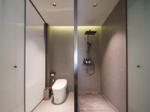 a bathroom with a toilet and a glass shower door at 桔作酒店 新乡东站市政府店 in Xinxiang