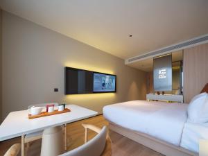 a hotel room with a large bed and a flat screen tv at 桔作酒店 新乡东站市政府店 in Xinxiang