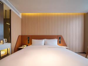 a bedroom with a large white bed in a room at 桔作酒店 新乡东站市政府店 in Xinxiang