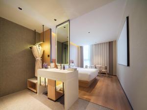 a bathroom with a bed and a sink and a mirror at 桔作酒店 新乡东站市政府店 in Xinxiang