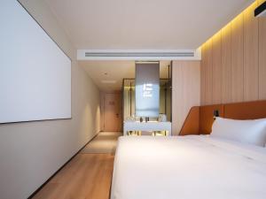a bedroom with a bed and a projection screen at 桔作酒店 新乡东站市政府店 in Xinxiang