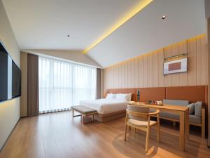 a hotel room with a bed and a desk and a bedroom at 桔作酒店 新乡东站市政府店 in Xinxiang