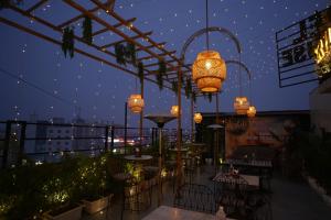 a rooftop patio with tables and chandeliers at night at HOTEL SILKHOUSE PREMIER in Dānāpur