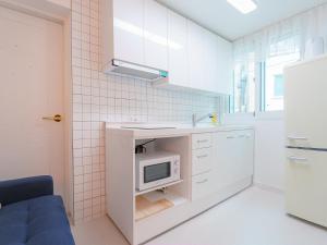 a white kitchen with a sink and a microwave at Hongik stay2 in Seoul
