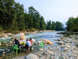 a group of people sitting at a table by a river at Apurwa Grand Resort in Baragrān